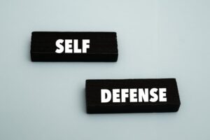 A coloured wooden block with text “SELF DEFENSE” on it