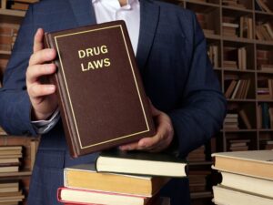 Attorney holds DRUG LAWS book. The possession, use, or distribution of illegal drugs is prohibited by federal law