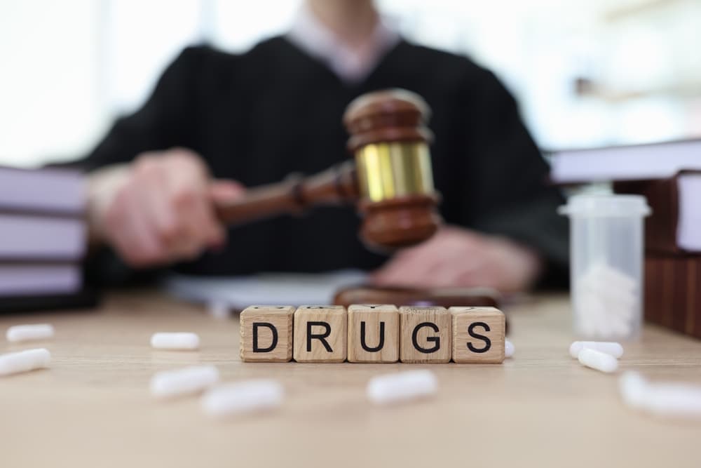 Word Drugs made with cubes and scattered pills on judge counter in courtroom