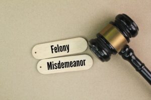 judge's hammer and stick with the words felony and misdemeanor